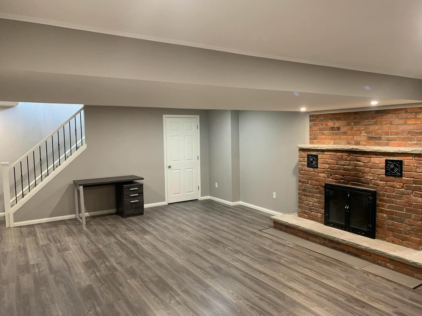 Basement living area with brick fireplace and vinyl plank